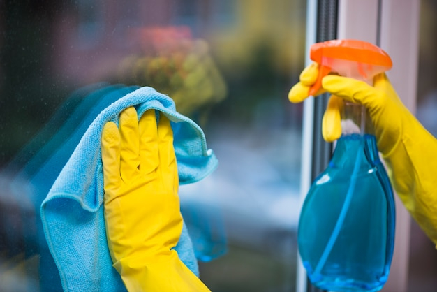 Janitor with yellow gloves cleaning glass window