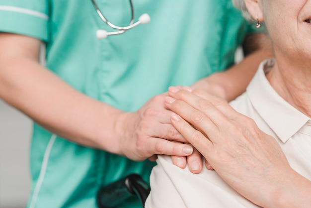 Senior woman patient touching female nurse hand on shoulder