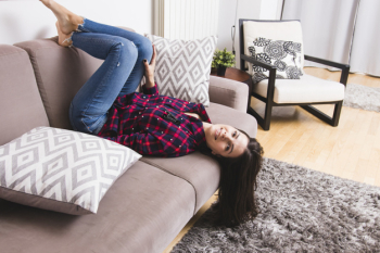 Smiling young woman lying upside down on sofa in the living room Free Photo