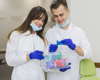 Dentists smiling and holding box of retainers Free Photo