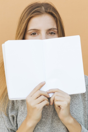 Blonde young woman holding blank book over her mouth against peach backdrop Free Photo