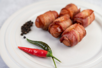 Sausage wrapped pork belly on a white plate. Free Photo