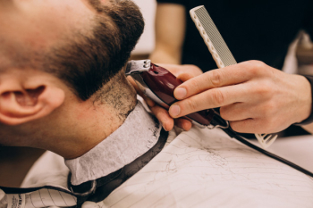 Man at a barbershop salon doing haircut and beard trim Free Photo