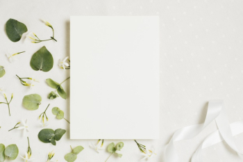 White blank wedding card with jasminum auriculatum flowers and ribbon on white backdrop Free Photo