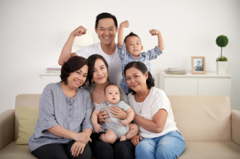 Asian extended family with baby and toddler posing together around couch at home Free Photo