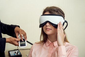 Girl is worried for her sight. relaxed modern european woman sitting in office of eye care specialist waiting when procedure will be finished, wearing digital vision screener during check-up Free Photo