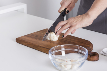 Woman's hand cutting the mushroom with knife on chopping board over the white table Free Photo