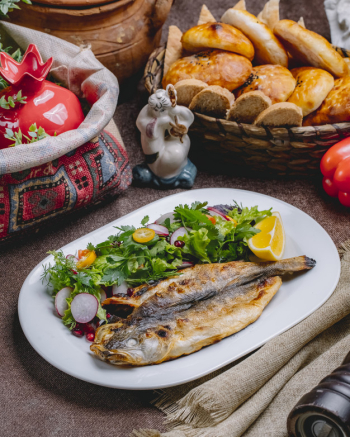 Side view grilled fish with a salad of vegetables and herbs with a slice of lemon Free Photo