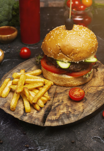 Fresh tasty beef burger and french fries on wooden table, ketchuo, tomatoes, vegetables Free Photo