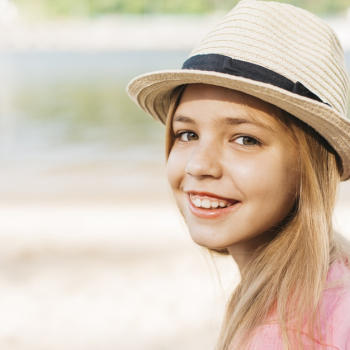 Smiling girl in hat at shore Free Photo