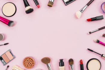Makeup cosmetics, brushes and other essentials on pink background Free Photo