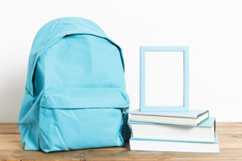 Blue schoolbag with empty frame on books on wooden table Free Photo