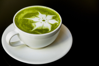 Latte flower art with japanese green tea matcha in cup on black backdrop