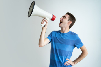 Excited attractive man shouting into megaphone