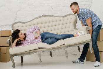 Man moving sofa with lying woman