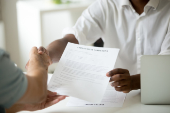 African-american employer holding employment agreement handshaking candidate, close up view