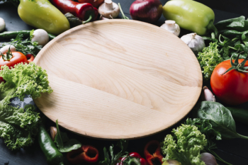 Elevated view of wooden tray surrounded with raw vegetables