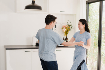 Young asian couple listen to music and dancing after having breakfast at home. attractive japanese woman and handsome man are enjoying spending time together in modern kitchen at house in the morning. Free Photo