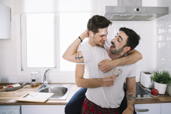 Happy gay couple having fun in kitchen