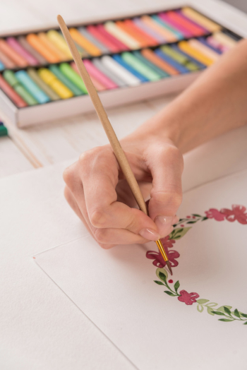 Young artist drawing flowers pattern with watercolor paint and brush at workplace Free Photo