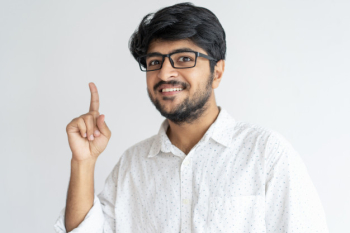 Smiling indian guy pointing upwards and looking at camera