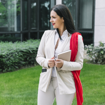 Professional businesswoman with diary standing outside office building