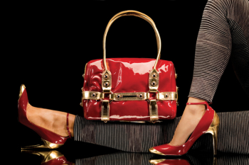 Leisure bag. A close-up of a chic red handbag along with sexy female legs wearing elegant red shoes.