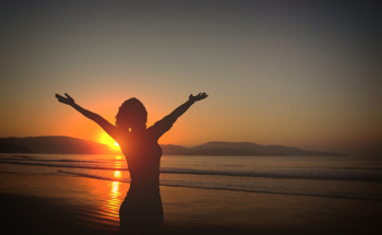  Young Woman on the Beach at Sunset with Raised Arms 