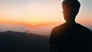 man's silhouette facing mountain at golden hour
