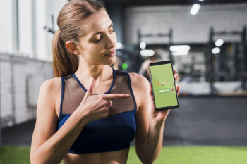Sporty woman pointing at smartphone mockup Free Psd
