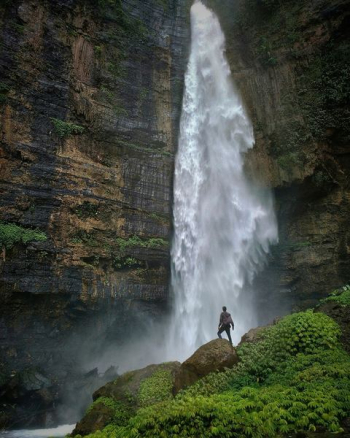 person standing on brown rock formation looking at waterfalls during daytime