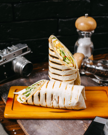 Side view of chicken doner wrapped in lavash on wooden table Free Photo