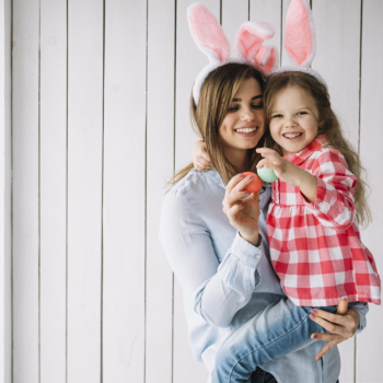 Young woman holding daughter in arms with easter eggs