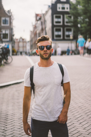 A man with a backpack walks through the streets of Amsterdam.