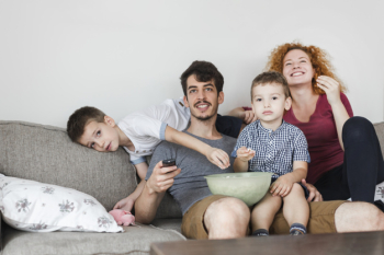 Family sitting on sofa watching television at home
