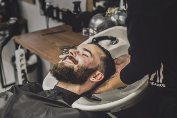 Cheerful client washing head in salon