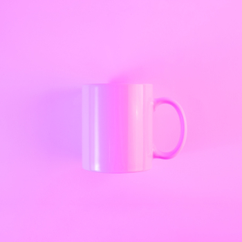 Painted pink mug with handle against colored background