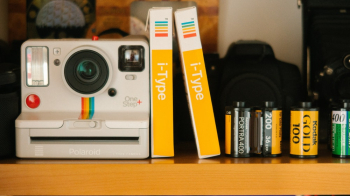 White Polaroid Land Camera Beside Photo Paper Boxes and Photo Films