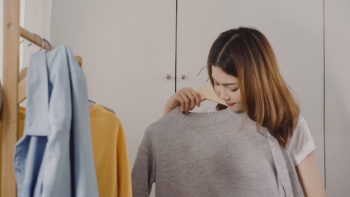 Beautiful attractive young asian woman choosing her fashion outfit clothes in closet at home