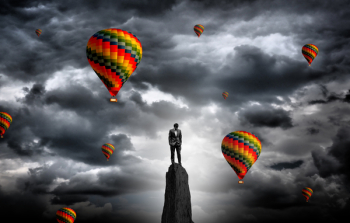  Businessman on the summit surrounded by hot air balloons - Ambit 