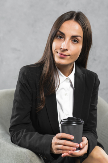 Portrait of a confident young businesswoman holding disposable coffee cup in hand