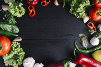 Elevated view of fresh vegetables forming circular frame on black background