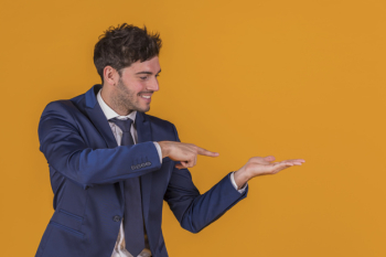 Portrait of a young businessman pointing his finger at something against an orange background Free Photo