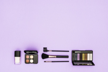Foundation bottle; eyeshadow palette and makeup brushes on purple background Free Photo