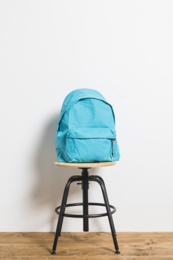 Blue schoolbag on stool chair on wooden surface Free Photo
