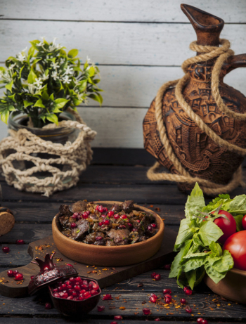 Lamb kebab slices garnished with pomegranate and herbs in clay pan Free Photo