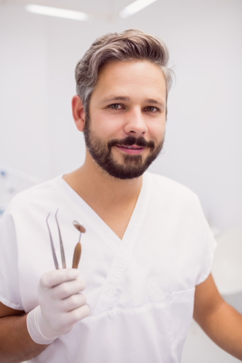Dentist holding dental tweezers and mouth mirror Free Photo