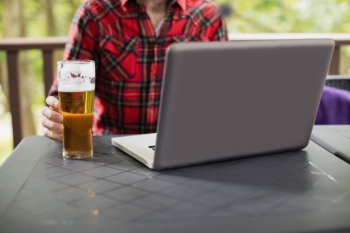 Man using laptop with glass of beer on table Free Photo