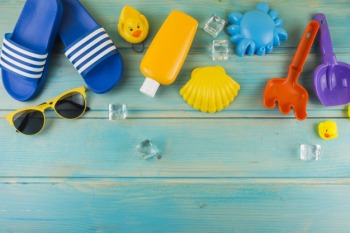 An elevated view of sunglasses; ice cubes; flip-flop; rubber duck; toys on turquoise wooden desk Free Photo