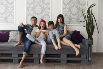 Parent and their children sitting together on sofa looking at camera Free Photo
